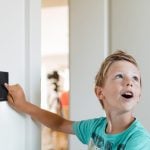 young child touching black box on the wall to demonstrate using Loxone product. NBG Digital Home. Electric Vehicle chargers, Solar and Heat Pumps, General Electrical Services in the South West.